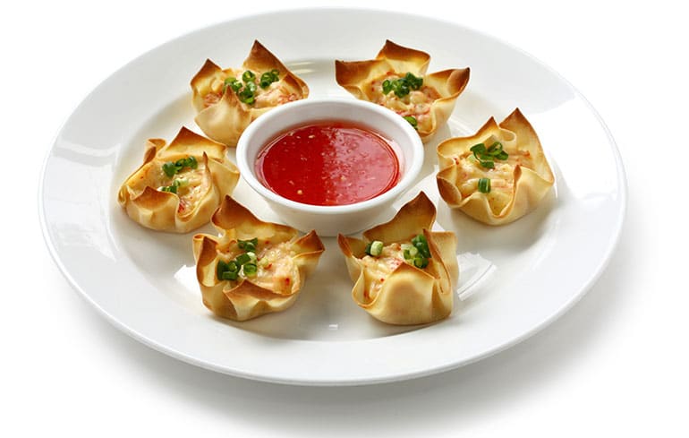 Wonton cups arranged in a circle on a white plate with a bowl of dipping sauce in the middle