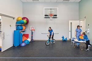 Gym with basketball hoop and colorful physical therapy balls