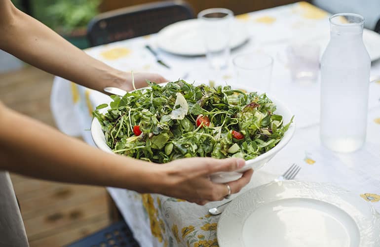 person holding a green salad over a table